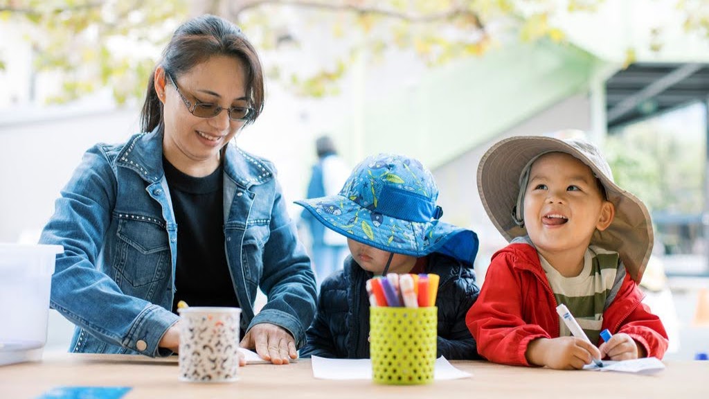 Preschool teacher speaking with children in the sandbox
